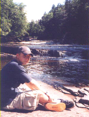 Stan Lemon sitting on rocks beside the Presque Isle River in Porcupine Mountains State Park