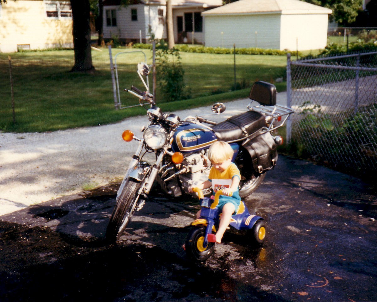 Young Stan Lemon on a tricycle next to a motorcycle in a driveway
